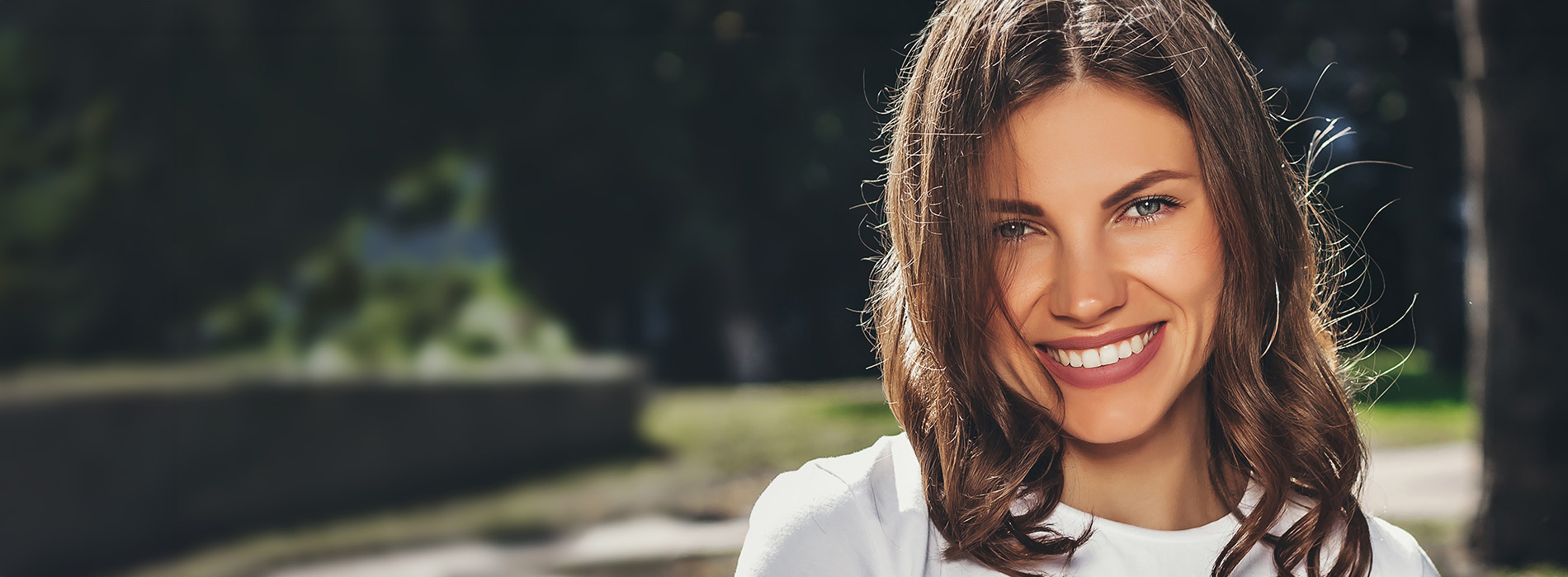 The image shows a woman with long hair smiling at the camera.